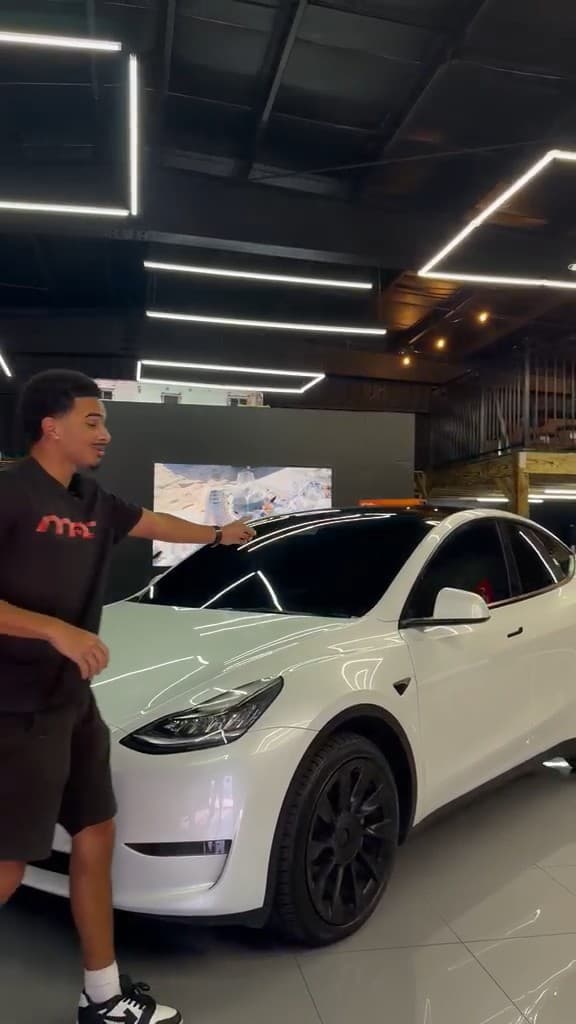 A MAD Custom team member walking alongside a white Tesla Model Y on the showroom floor